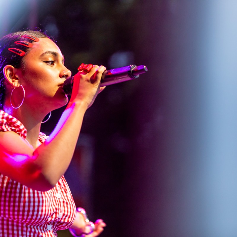 Chovo hält ein Mikrofon an den Mund und singt beim Kultursommer Wien 2025. 