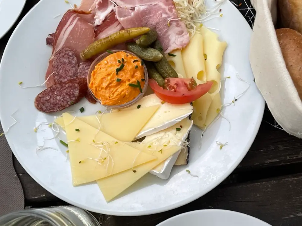 Auf dem Bild sieht man einen Teller mit Käse, Wurst und Aufstrich. 