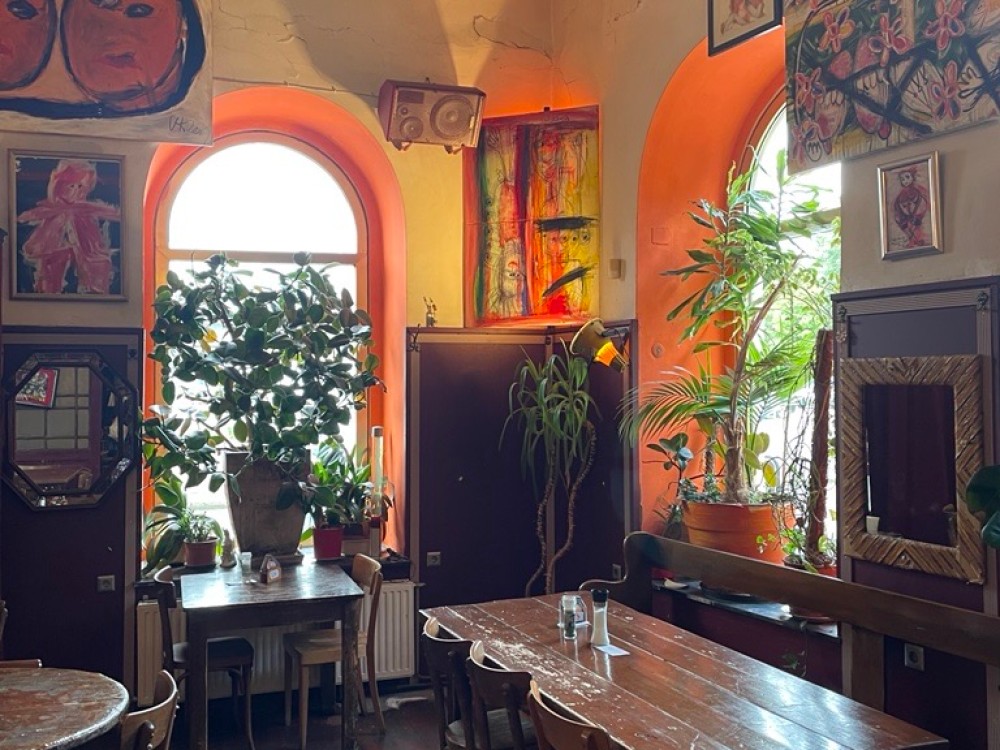 Ein Restaurant, es ist hell. Kunst hängt an der Wand, hölzerner Boden.