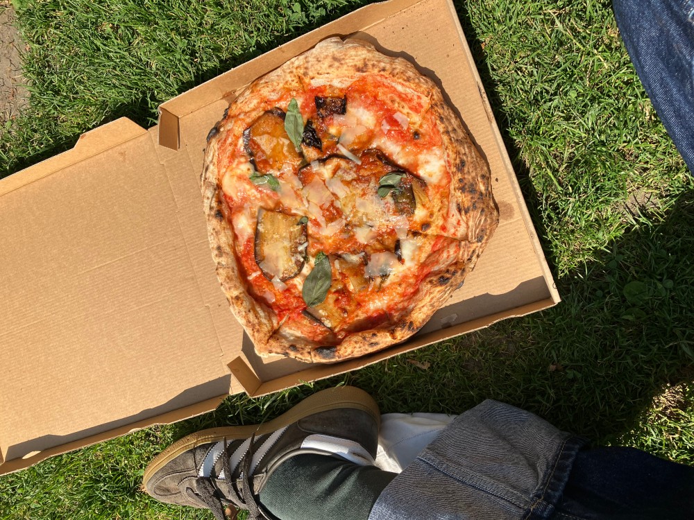 Ein Foto von einer Pizza die auf einer Wiese liegt.
