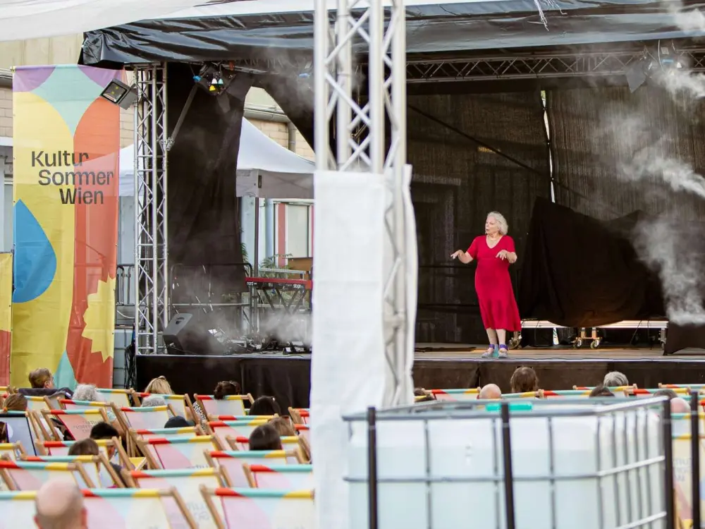 Jenny Simanowitz: Jenny Simanowitz bringt ihre Comedyshow auf die Kultursomemr-Bühne beim Nordwestbahnhof. Sie gestikuliert mit ihren Armen. 