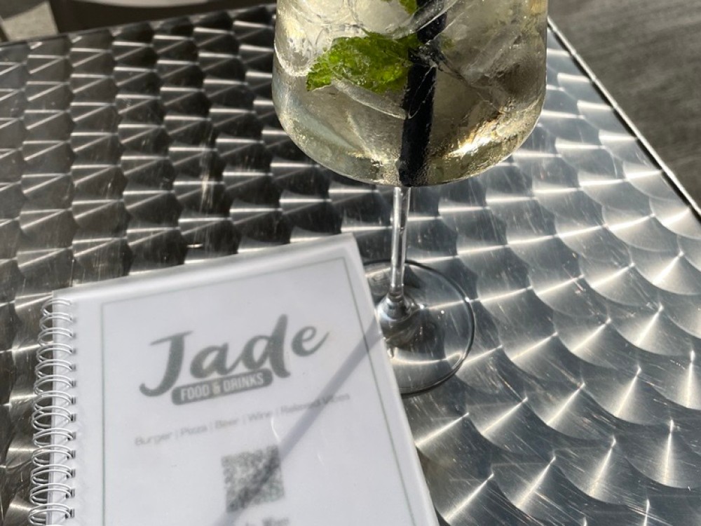 Ein Getränk im Weinglas mit Minzblättern und eine Speisekarte