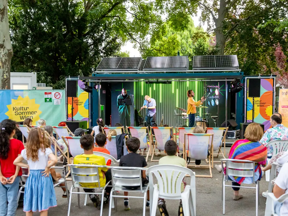 Viele Menschen sitzen vor der Kultursommerbühne im Kongreßpark. 