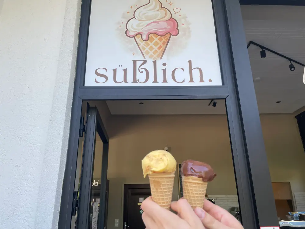 Ein Mangoeis und ein Schokoeis werden vor den Eissalon Süßlich gehalten. 