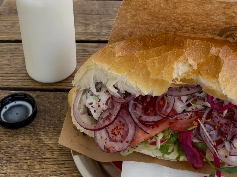 Auf dem Bild ist ein Kebap mit Falafel und ein Ayran zu sehen. 