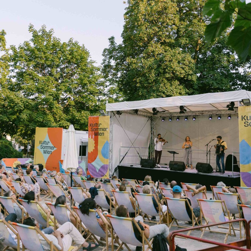 Foto: Niko Havranek Wienerlied-Konzert auf der Bühne im Reithofferpark. Das Publikum sitzt in den Liegstühlen und lauscht der Band.