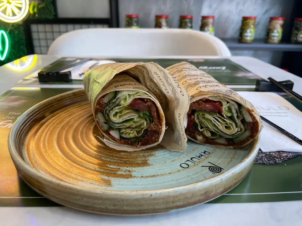 Ein Çiğköfte Wrap liegt auf einem Teller. 